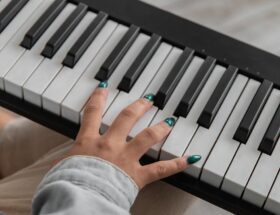 unrecognizable female musician playing synthesizer on couch
